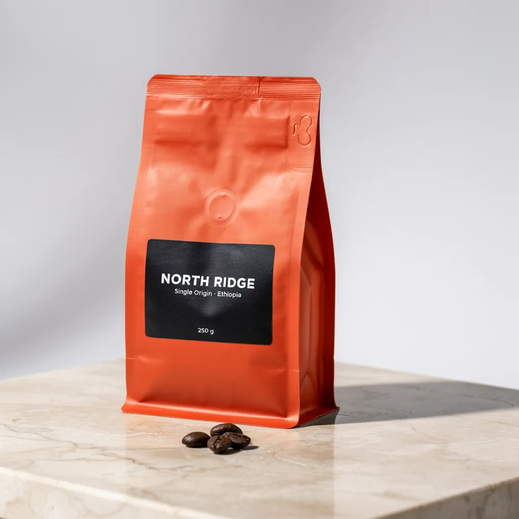 The same coffee bag after the edit, now terracotta orange with the same NORTH RIDGE label