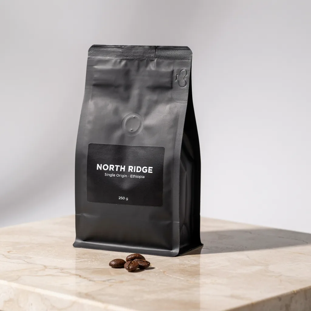 Matte black coffee bag with a label that reads NORTH RIDGE on a stone surface